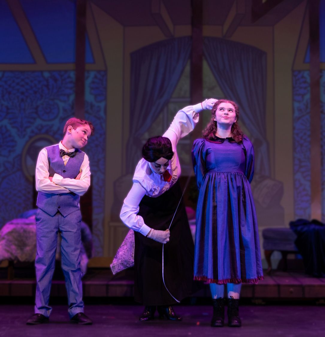 Parker Pitt as Jane Banks being measured by Mary Poppins in Mary Poppins at TheaterWorks