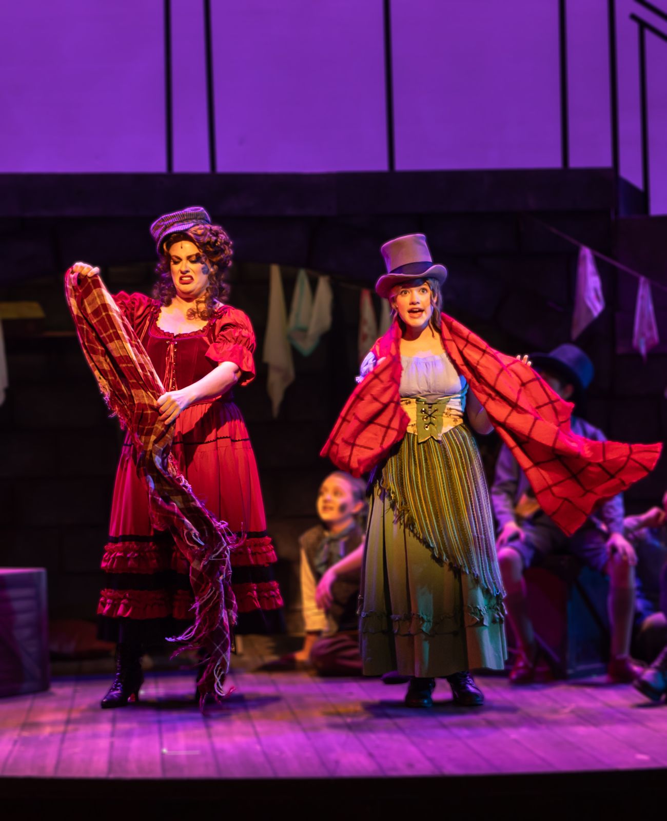 Parker Pitt as Bet in a red shawl and top hat with another actor in Oliver! at TheaterWorks