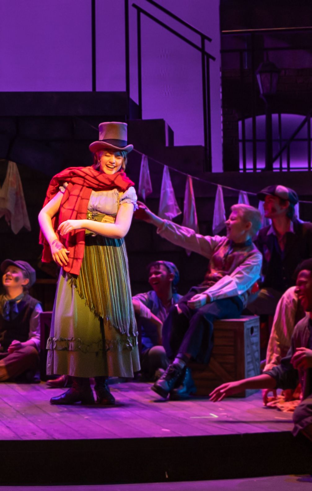 Parker Pitt as Bet in a red shawl and top hat in Oliver! at TheaterWorks