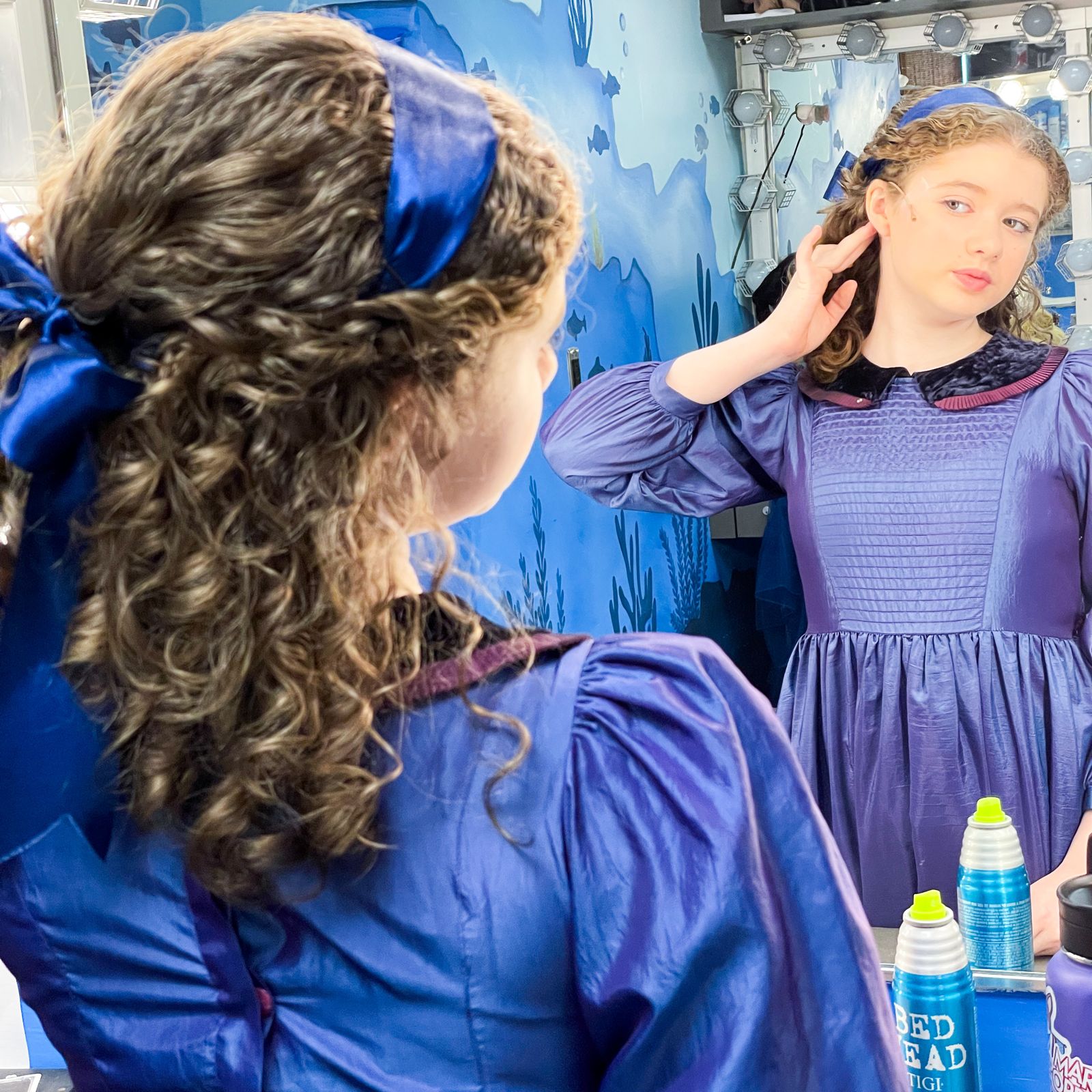 Parker Pitt in costume as Jane Banks looking into a dressing-room mirror backstage at Mary Poppins, TheaterWorks