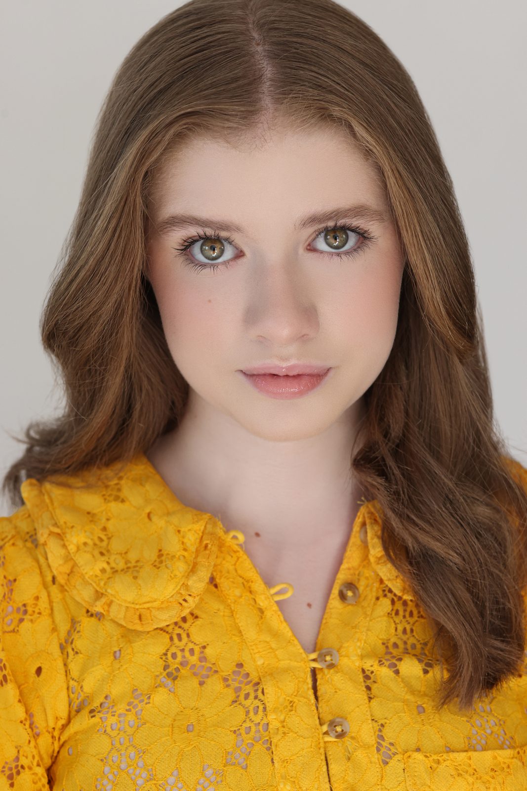 Parker Pitt, actor, 2025 headshot in a yellow lace blouse on a light background by Lilly K Photography