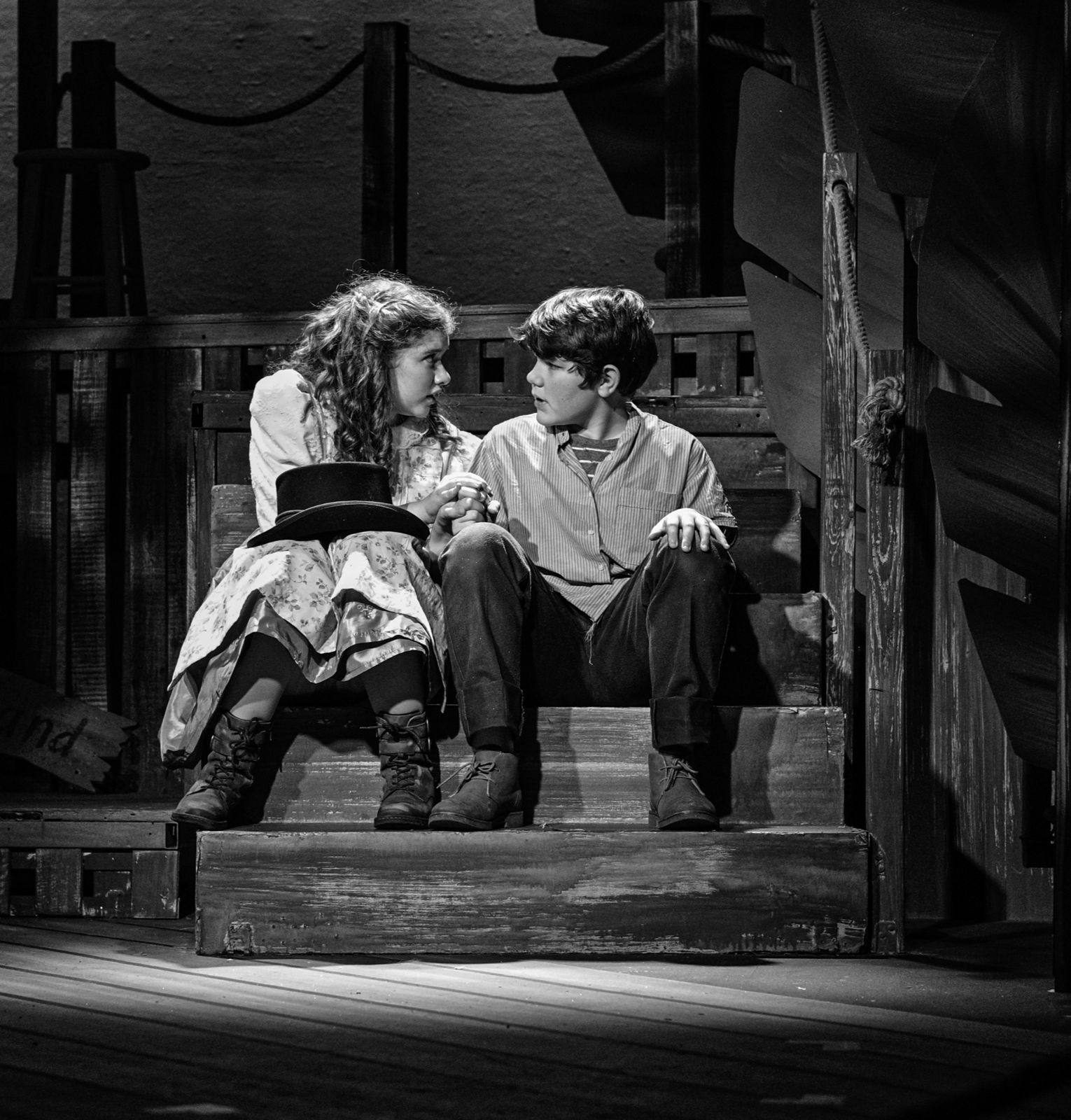 Parker Pitt as Molly Aster sitting on the stairs with Peter in Peter and the Starcatcher at Valley Youth Theatre, black and white