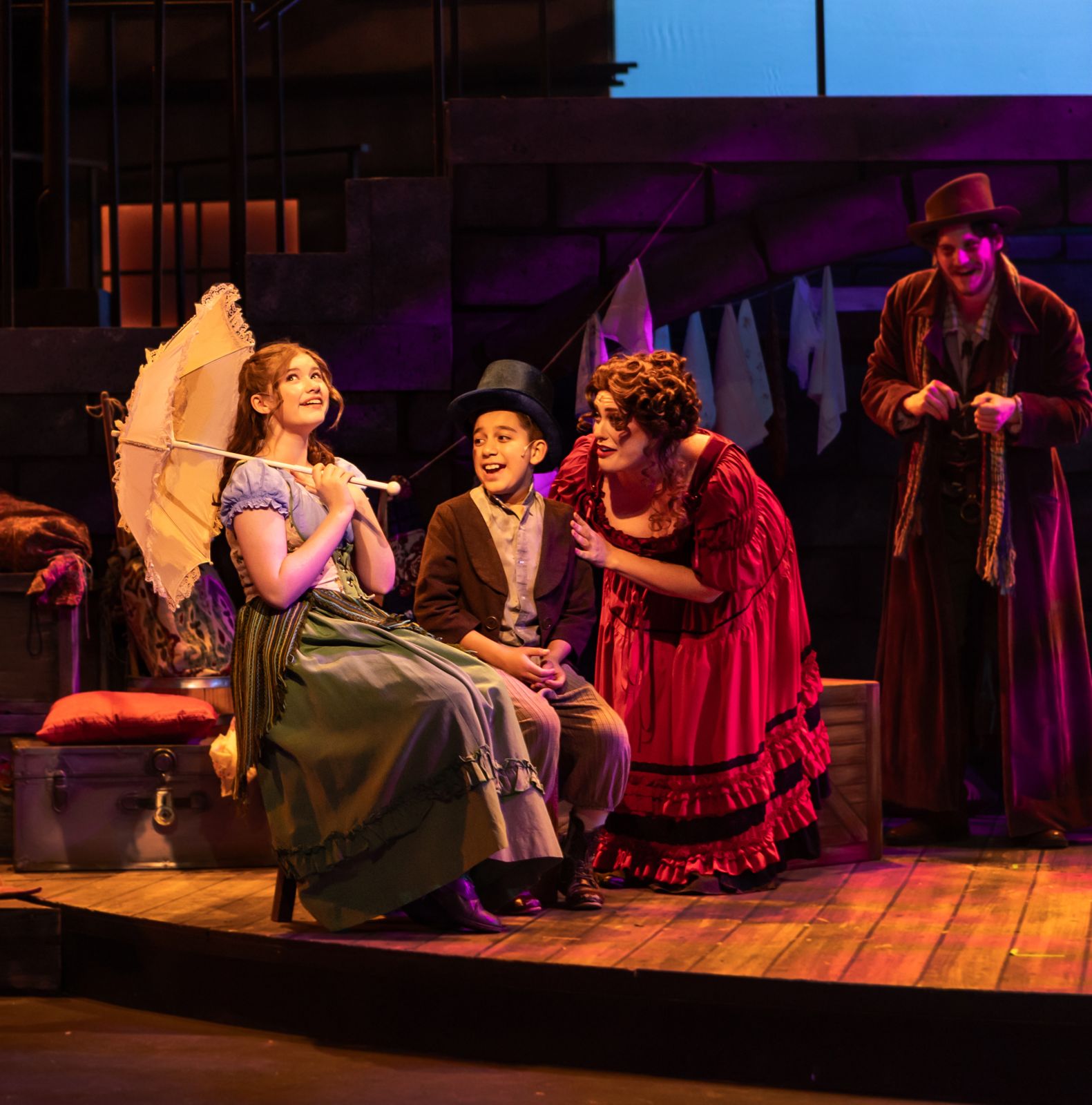 Parker Pitt as Bet holding a parasol in a street scene in Oliver! at TheaterWorks