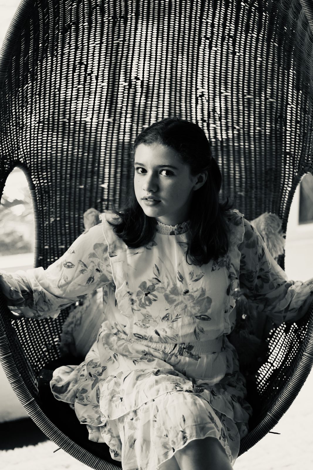 Parker Pitt sitting in an oversized wicker chair, black and white