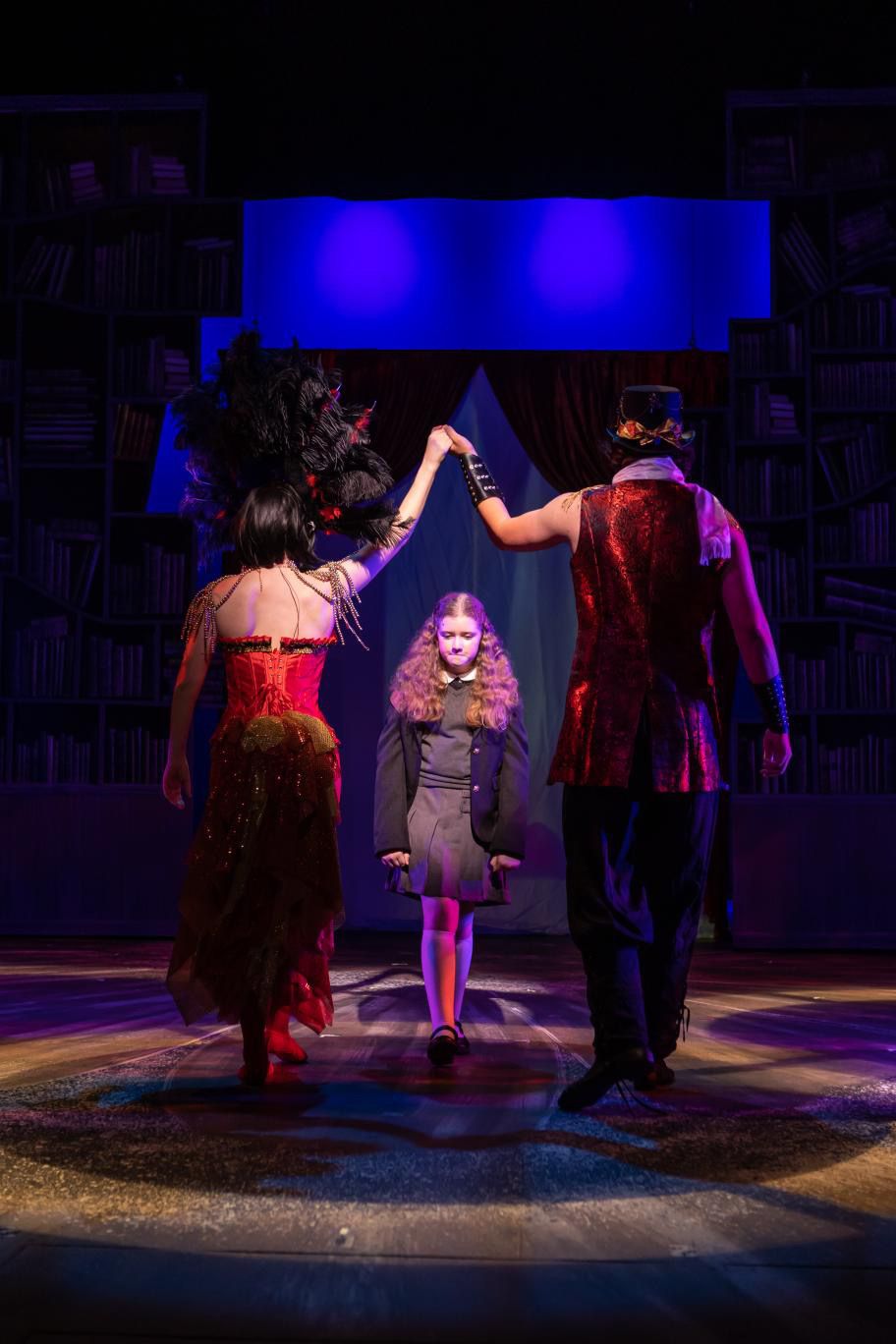Parker Pitt as Matilda walking between the Acrobat and the Escapologist in Matilda the Musical at TheaterWorks