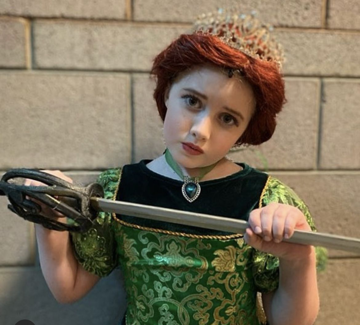 Parker Pitt as Young Fiona wearing a crown and holding a sword in Shrek the Musical at Mesa Encore Theatre