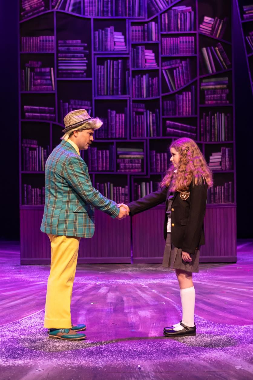 Parker Pitt as Matilda shaking hands with Mr Wormwood in Matilda the Musical at TheaterWorks